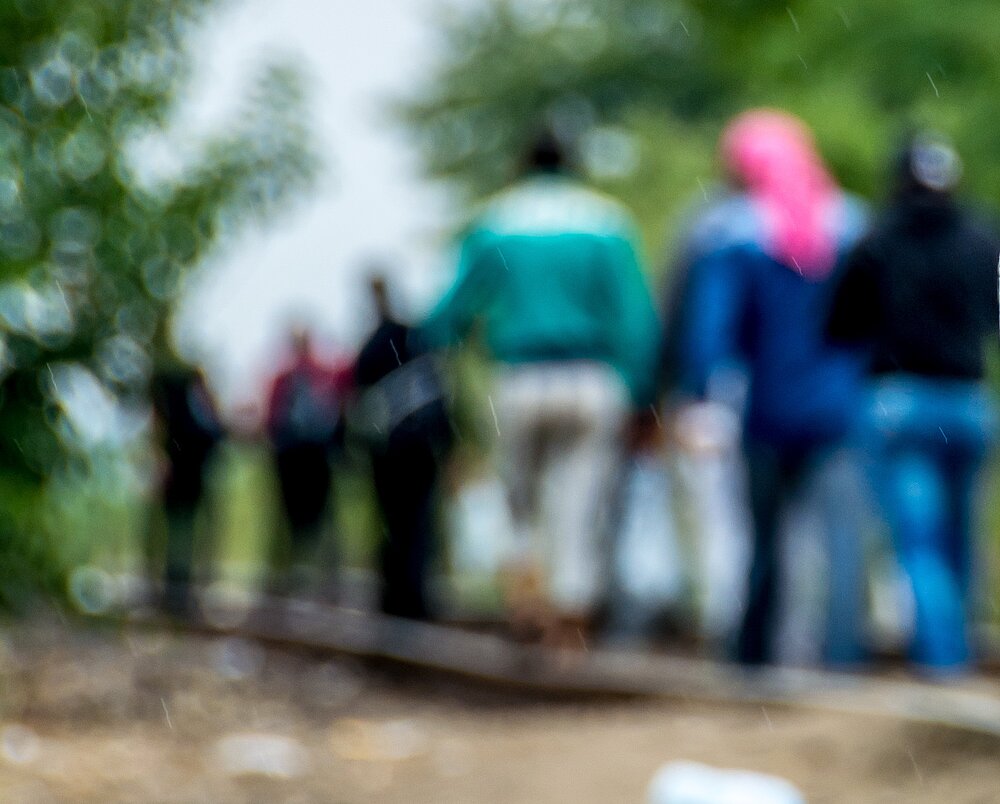 A blurry image of people walking down a trail track. 