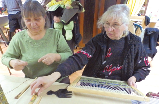 Deux femmes s'assoient à une table et tissent quelque chose ensemble.