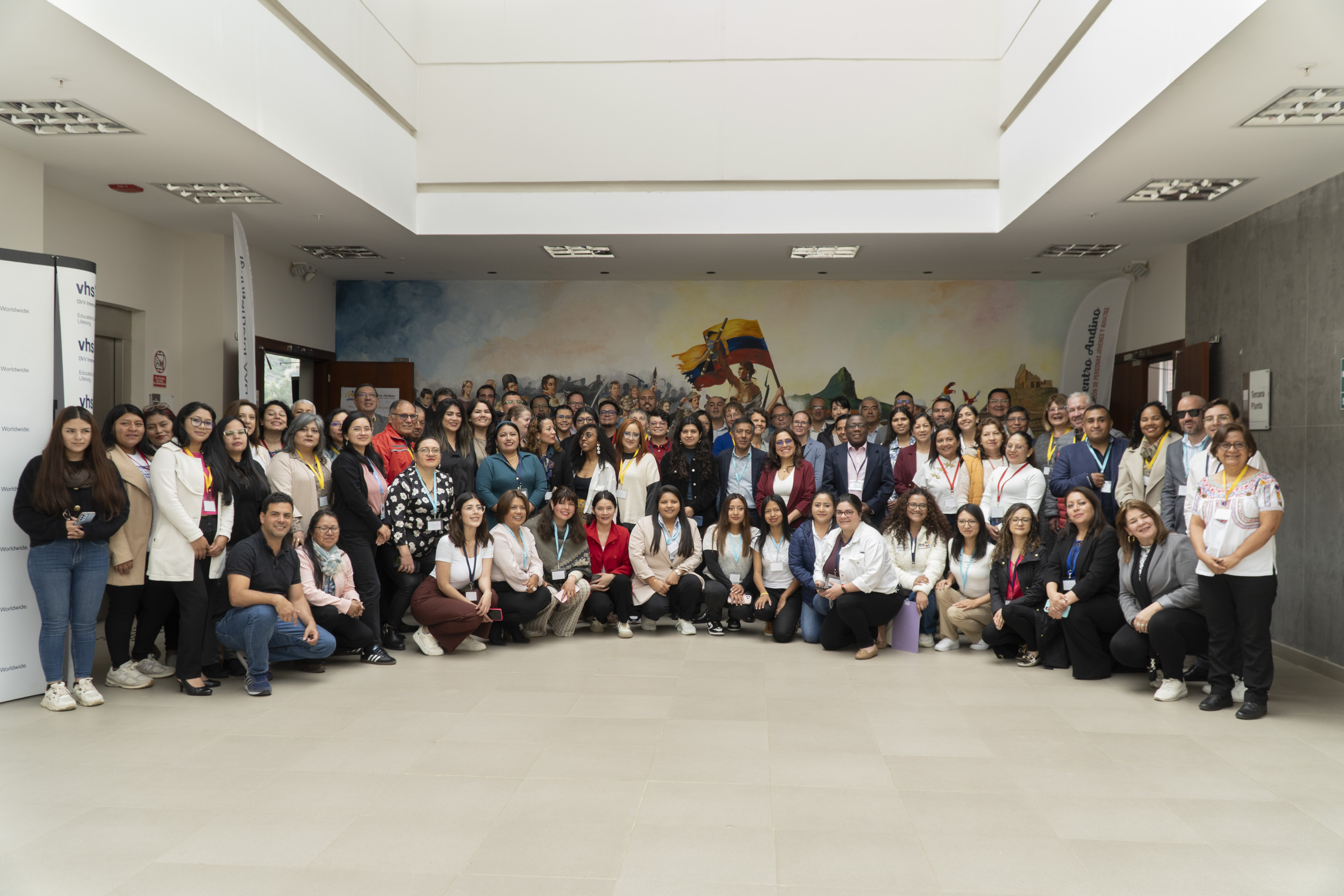 A large group of people stand together for a group photo and look into the camera.